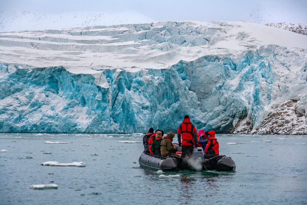Adventure tourists at the terminus of the Monaco Glacier in Woodfjorden in the Svalbard Islands (Spitsbergen) in the high Arctic.