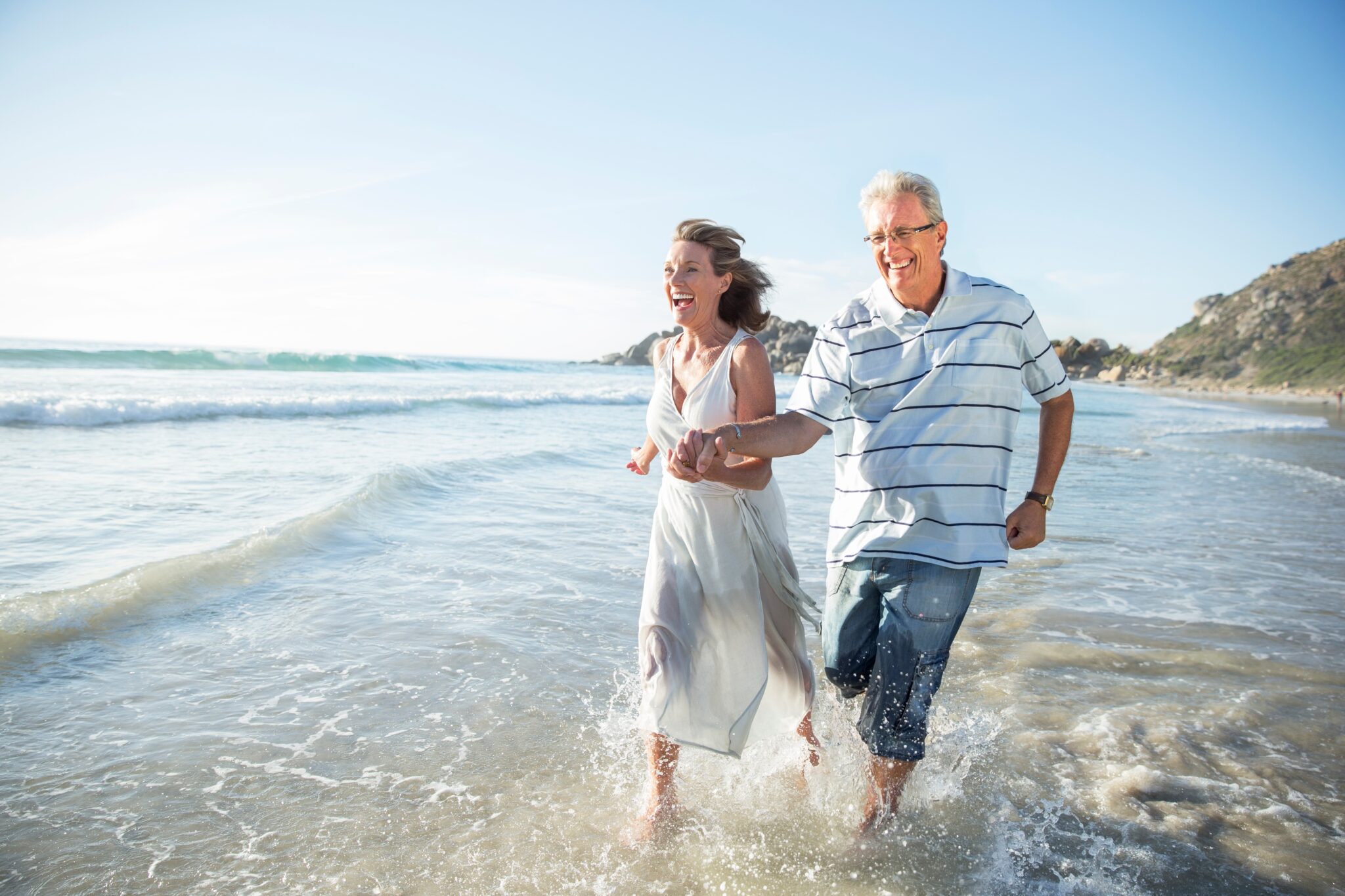 Older,Couple,Playing,In,Waves,On,Beach
