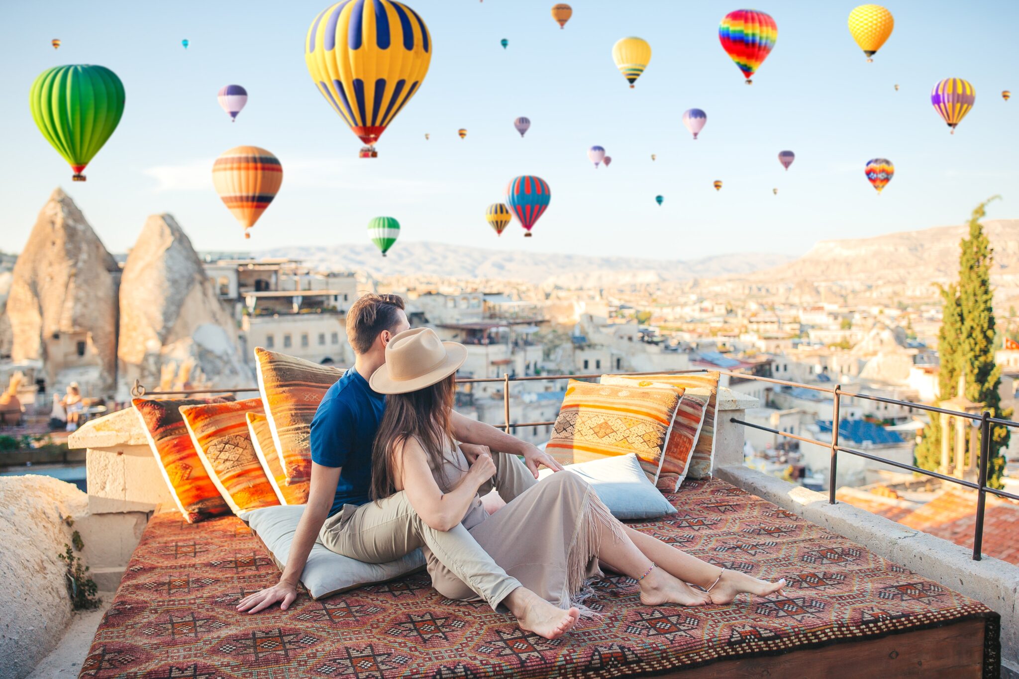 Happy,Couple,On,A,Rooftop,In,Cappadocia,With,Hot,Air